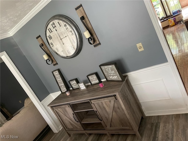 room details with crown molding, a decorative wall, wood finished floors, and a wainscoted wall