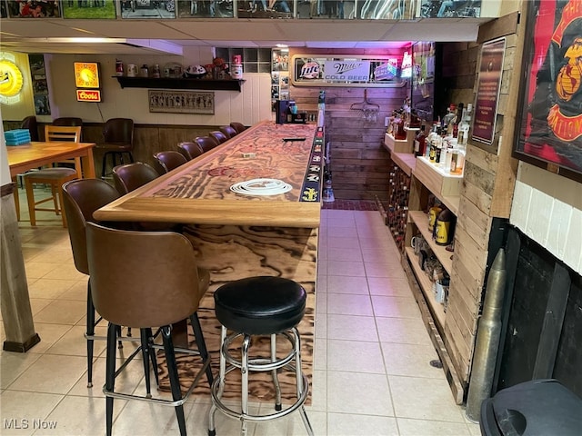 bar with tile patterned floors, a dry bar, and wooden walls