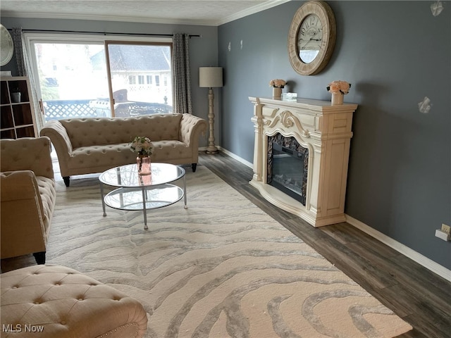 living room with baseboards, wood finished floors, a glass covered fireplace, and crown molding