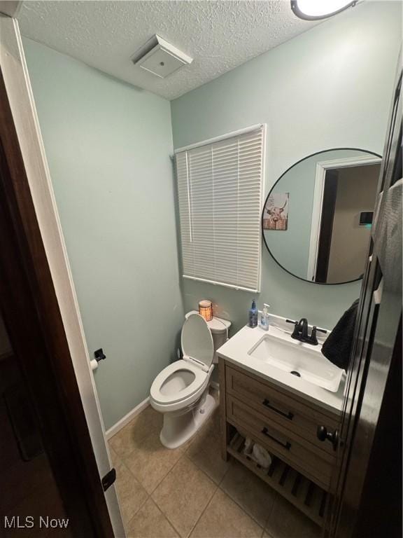 bathroom featuring tile patterned floors, toilet, a textured ceiling, baseboards, and vanity