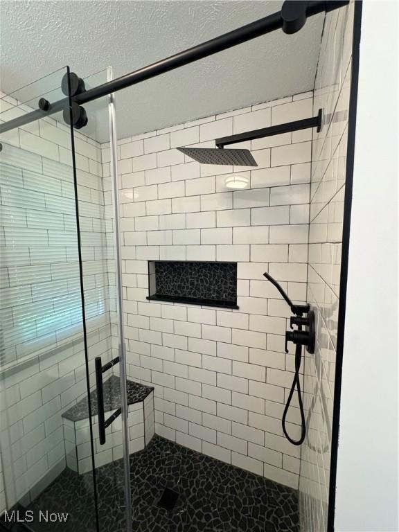 full bathroom featuring a shower stall and a textured ceiling