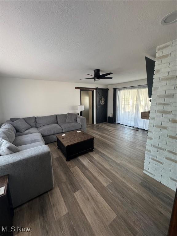 living area featuring ceiling fan, a textured ceiling, and wood finished floors