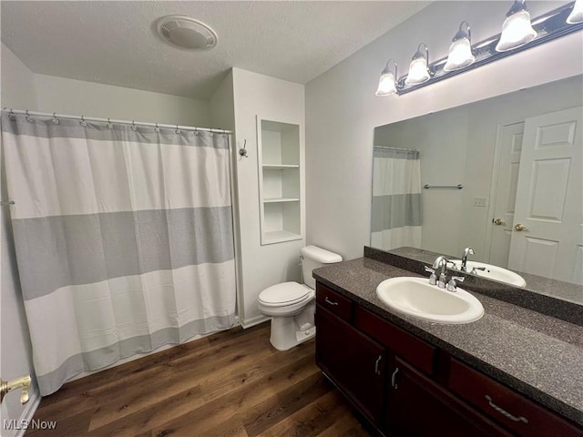 bathroom featuring visible vents, toilet, vanity, wood finished floors, and a textured ceiling