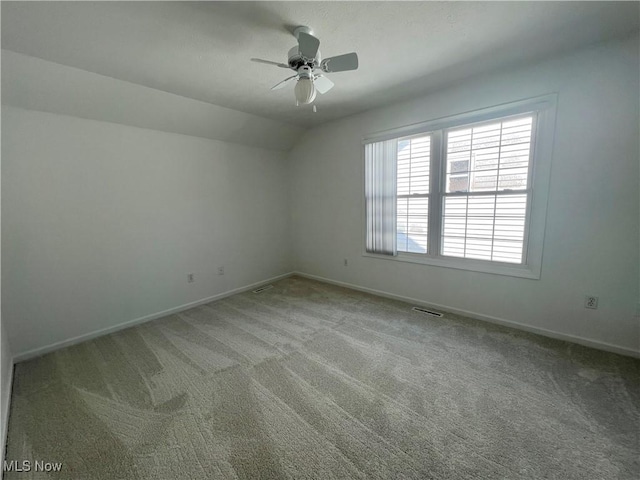 unfurnished room featuring lofted ceiling, light colored carpet, visible vents, and baseboards