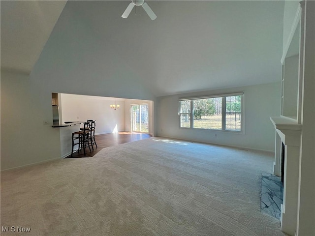 unfurnished living room featuring high vaulted ceiling, ceiling fan with notable chandelier, a large fireplace, carpet flooring, and baseboards