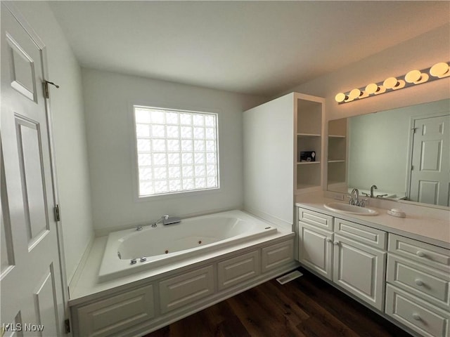 bathroom featuring a tub with jets, vanity, and wood finished floors