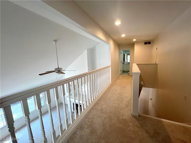 corridor with visible vents, baseboards, recessed lighting, an upstairs landing, and light colored carpet