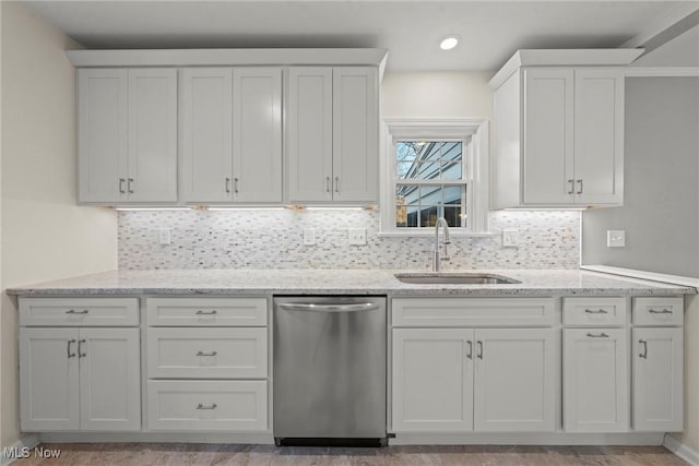 kitchen featuring light stone countertops, a sink, white cabinets, dishwasher, and backsplash