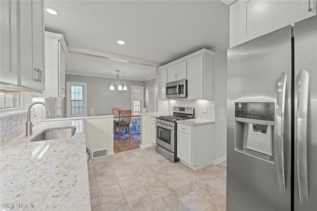 kitchen with a sink, light stone counters, stainless steel appliances, white cabinets, and decorative backsplash