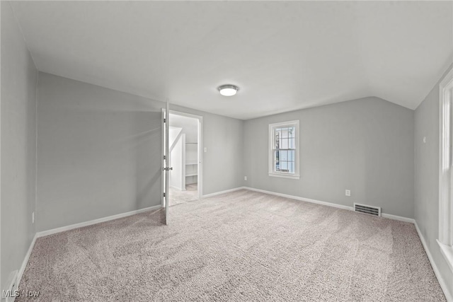 interior space featuring visible vents, carpet floors, baseboards, and vaulted ceiling