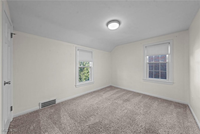 carpeted spare room with visible vents, lofted ceiling, and baseboards