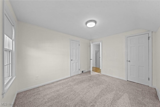 unfurnished bedroom featuring visible vents, carpet floors, and baseboards