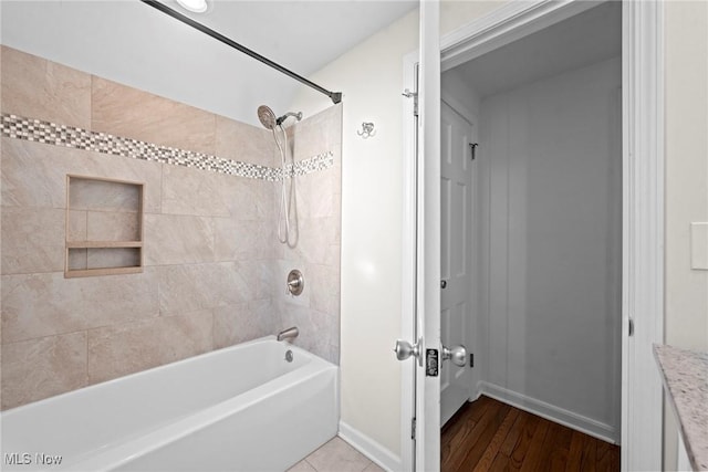 bathroom with shower / bathing tub combination, wood finished floors, and baseboards