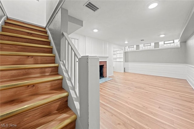 interior space featuring visible vents, a wainscoted wall, recessed lighting, a fireplace, and wood finished floors