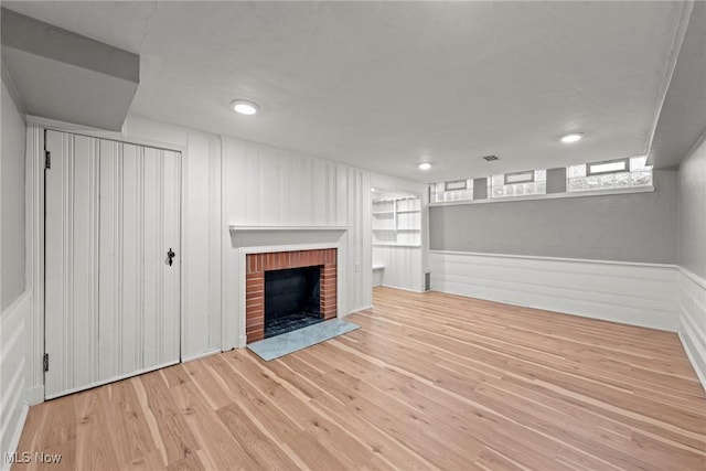 unfurnished living room featuring visible vents, a fireplace, and wood finished floors