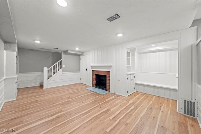 basement featuring visible vents, a fireplace, stairway, and wood finished floors