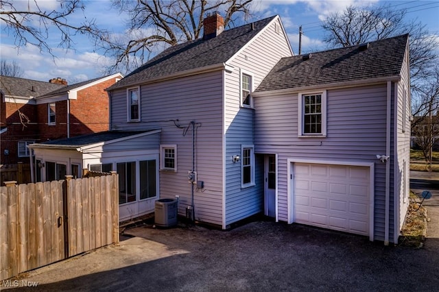 back of property with cooling unit, fence, a garage, and driveway