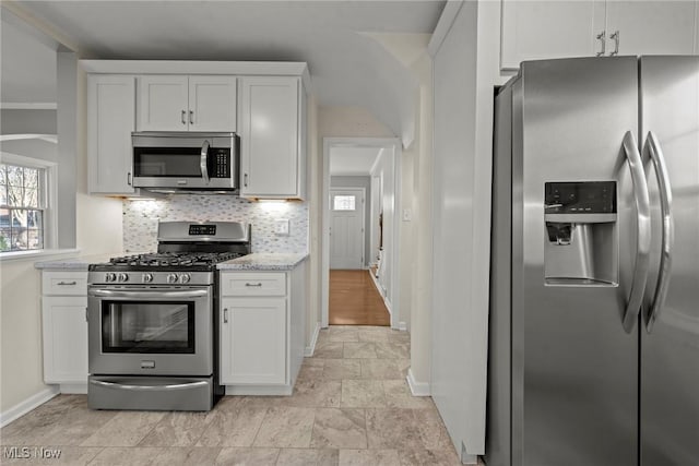 kitchen with white cabinetry, light stone countertops, tasteful backsplash, and appliances with stainless steel finishes