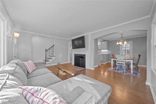 living area featuring a fireplace, stairs, baseboards, and wood finished floors