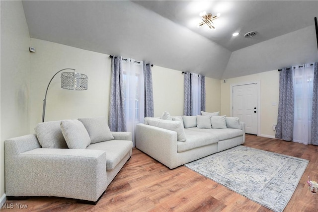 living room featuring visible vents, baseboards, lofted ceiling, and wood finished floors