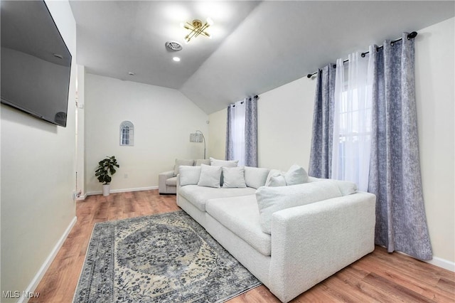 living area with visible vents, baseboards, lofted ceiling, and light wood-style floors