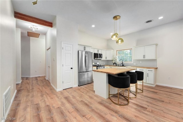 kitchen with a sink, tasteful backsplash, white cabinetry, appliances with stainless steel finishes, and wooden counters