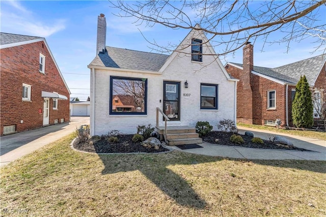 view of front of house with a front lawn, brick siding, roof with shingles, and a chimney