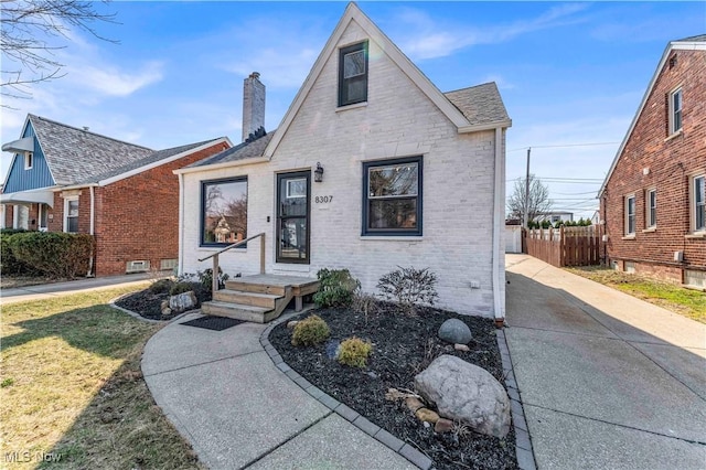 view of front of property featuring brick siding, fence, roof with shingles, a chimney, and driveway