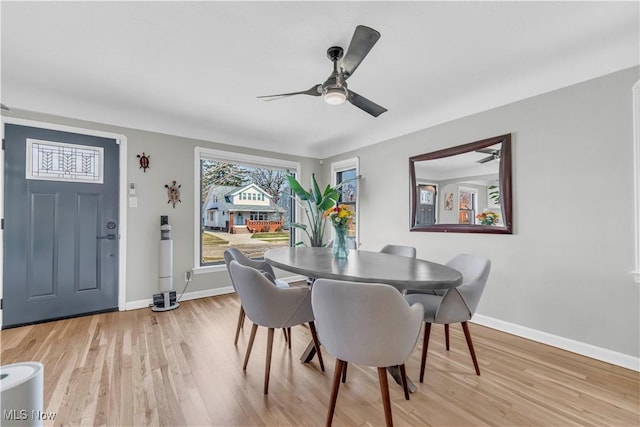 dining area with baseboards, a ceiling fan, and light wood finished floors