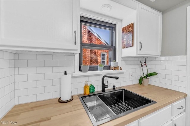 kitchen featuring white cabinetry, decorative backsplash, wood finished floors, and a sink