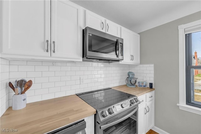 kitchen with tasteful backsplash, appliances with stainless steel finishes, plenty of natural light, white cabinetry, and wood counters