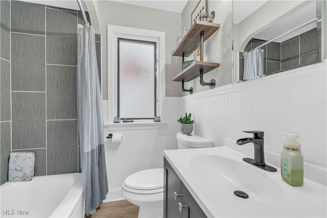 full bathroom with vanity, wood finished floors, a wainscoted wall, shower / tub combo, and toilet