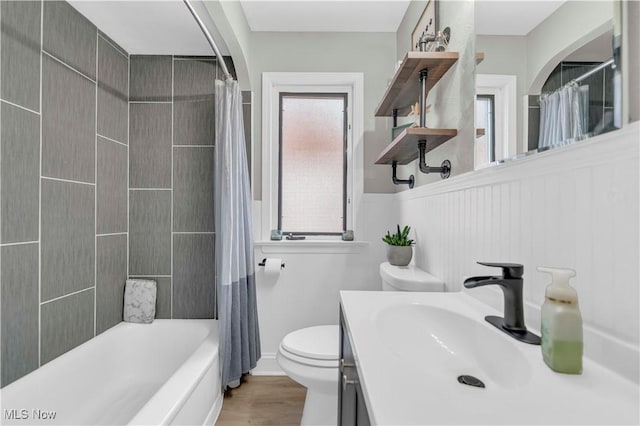 full bathroom with a wainscoted wall, toilet, shower / tub combo with curtain, wood finished floors, and vanity