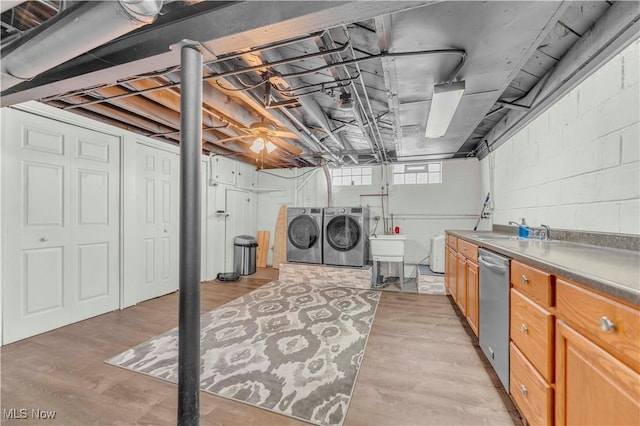 basement featuring light wood-style flooring, separate washer and dryer, and a sink