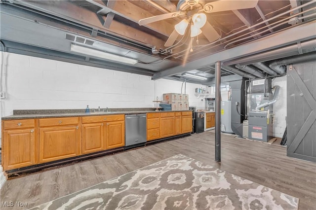 basement featuring a sink, heating unit, concrete block wall, and light wood finished floors