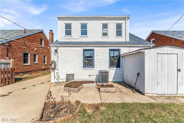 back of house with fence, central AC unit, an outdoor structure, a storage unit, and a patio