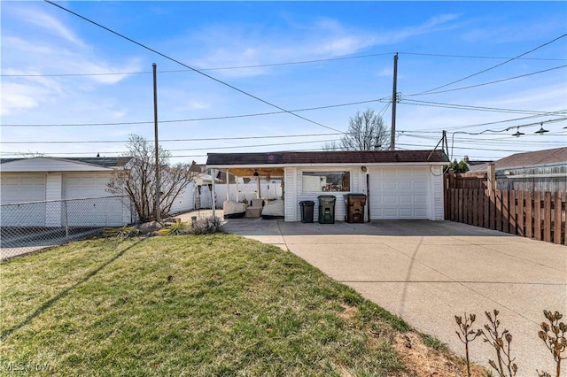 view of front facade with an outdoor structure, concrete driveway, a front yard, and fence