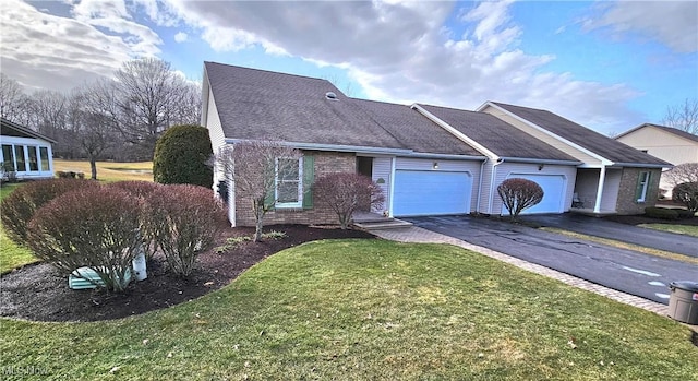 ranch-style home featuring driveway, roof with shingles, a front yard, a garage, and brick siding