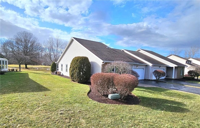 view of side of property with a lawn, a garage, and driveway