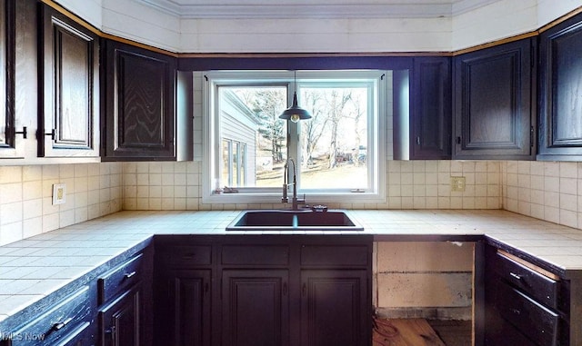 kitchen featuring a sink, backsplash, and tile countertops