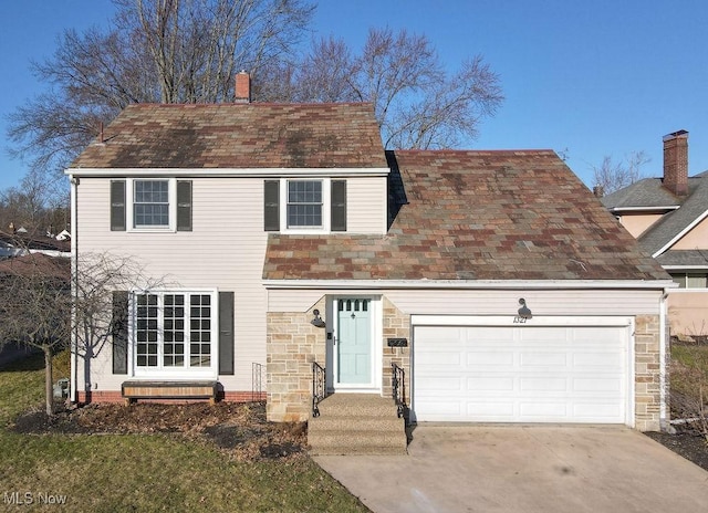 view of front of house with stone siding, driveway, a chimney, and a garage