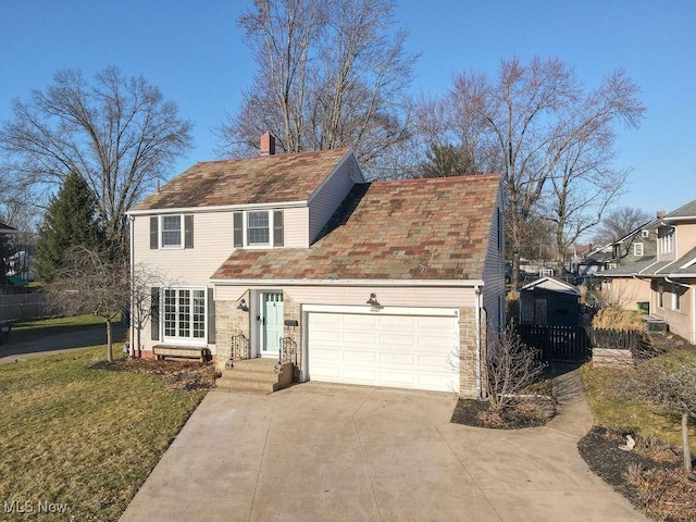 view of front of home featuring driveway, a front yard, a chimney, and an attached garage