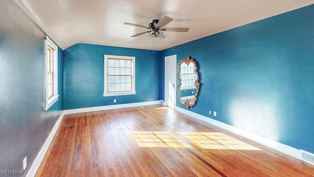 empty room with hardwood / wood-style floors, vaulted ceiling, baseboards, and ceiling fan