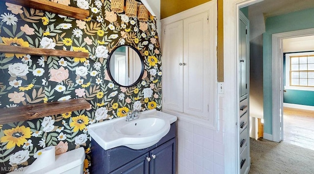 half bath featuring baseboards, toilet, vanity, and wallpapered walls