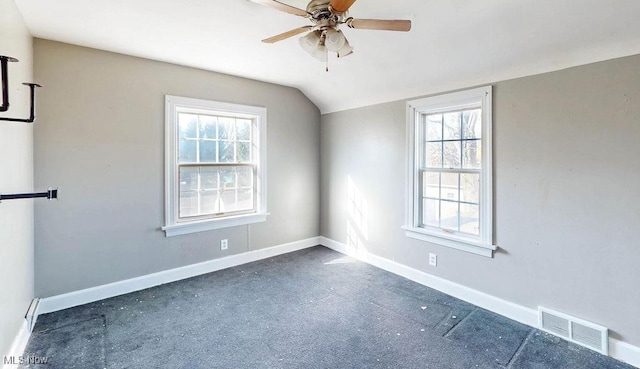 unfurnished room featuring lofted ceiling, baseboards, visible vents, and ceiling fan