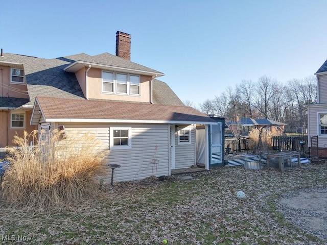 back of property featuring a chimney and roof with shingles