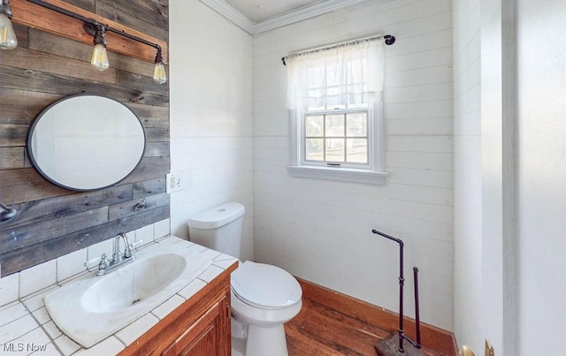 half bath with vanity, wooden walls, toilet, and wood finished floors