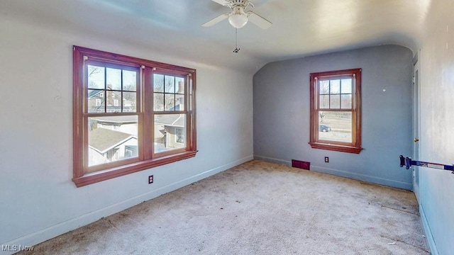 carpeted empty room featuring baseboards, ceiling fan, and vaulted ceiling