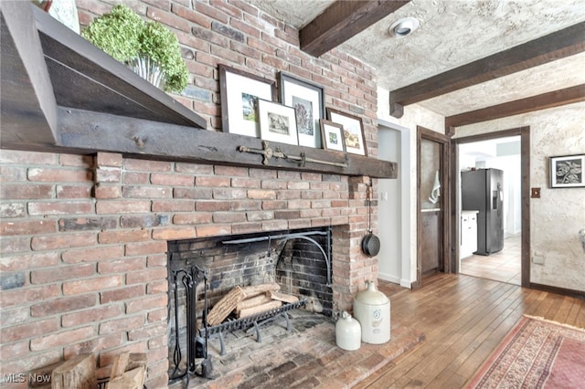 interior details with stainless steel fridge, a brick fireplace, baseboards, and wood finished floors