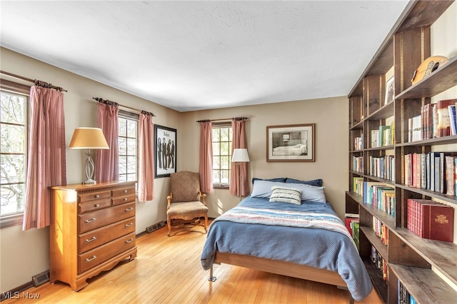 bedroom with baseboards, visible vents, and light wood finished floors